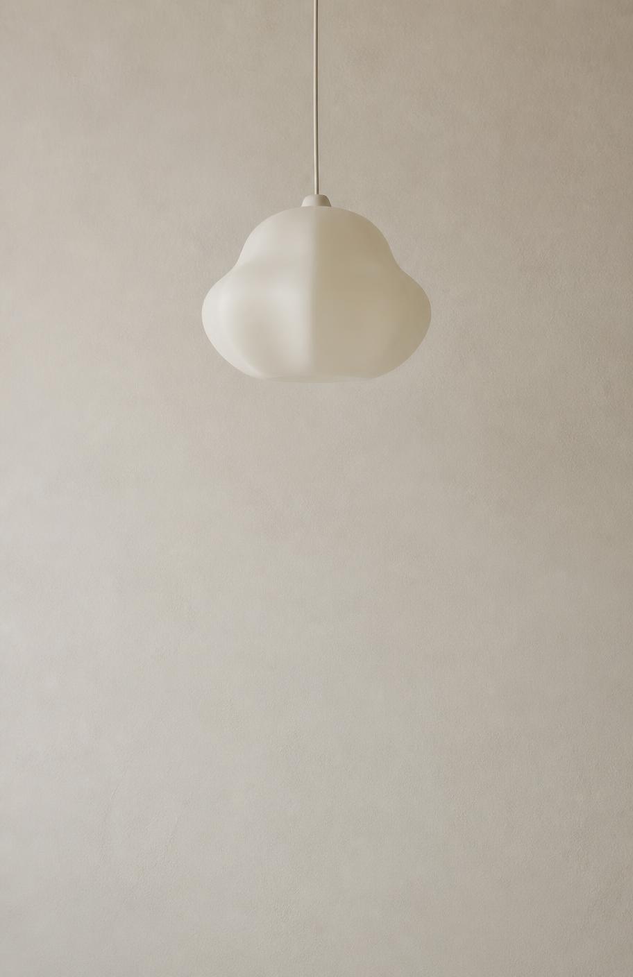 Stratus pendant in brushed brass hanging above an oak dining table